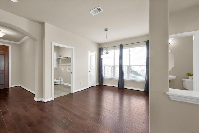 unfurnished dining area with arched walkways, dark wood-style flooring, visible vents, and baseboards