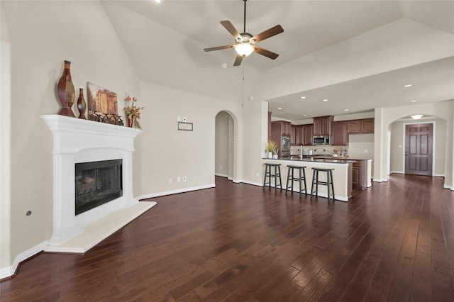 unfurnished living room featuring dark wood-type flooring, high vaulted ceiling, and ceiling fan