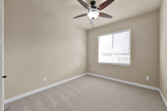 carpeted spare room featuring a ceiling fan and baseboards