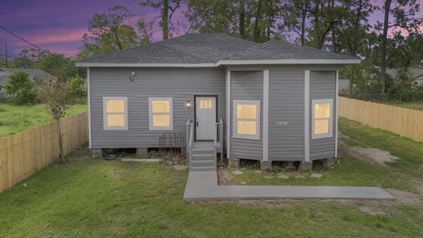 back house at dusk with a lawn