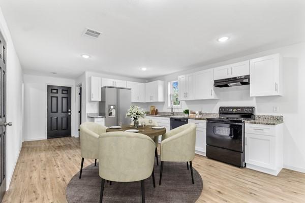 kitchen with black appliances, light hardwood / wood-style floors, and white cabinets