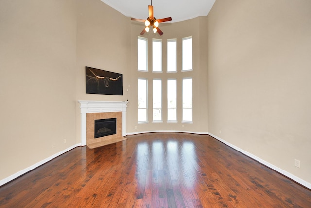 unfurnished living room featuring ceiling fan, dark hardwood / wood-style floors, and a tile fireplace