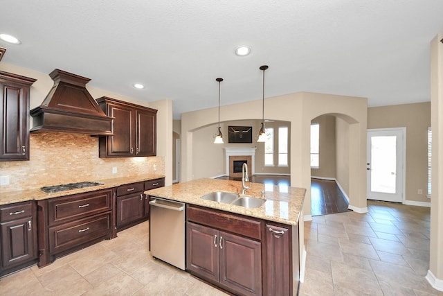 kitchen featuring sink, an island with sink, pendant lighting, custom range hood, and appliances with stainless steel finishes