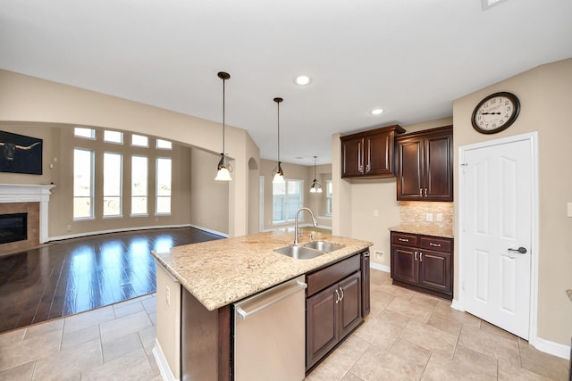 kitchen with sink, stainless steel dishwasher, an island with sink, tasteful backsplash, and dark brown cabinetry