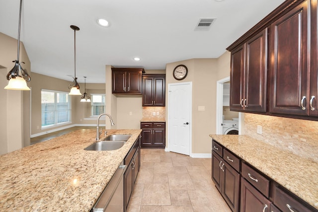 kitchen featuring backsplash, light stone countertops, sink, and hanging light fixtures