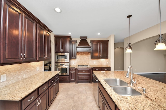 kitchen with backsplash, custom exhaust hood, stainless steel appliances, sink, and decorative light fixtures