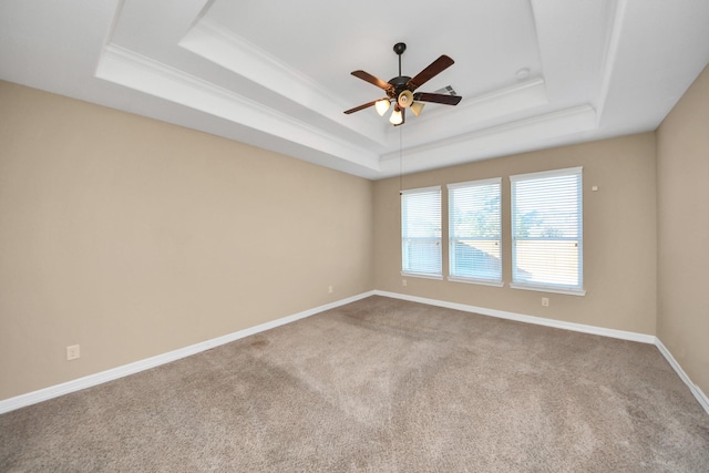 empty room with a tray ceiling, ceiling fan, and carpet flooring