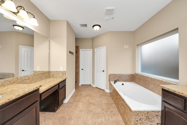 bathroom with tile patterned flooring, vanity, and tiled tub