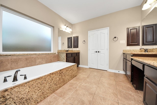 bathroom with tile patterned flooring, vanity, and tiled bath