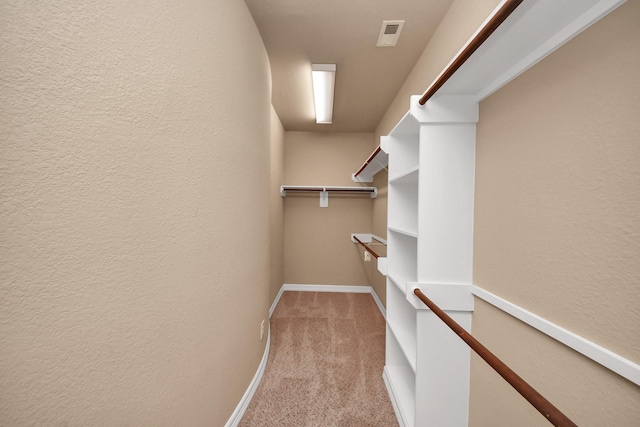 walk in closet featuring light colored carpet