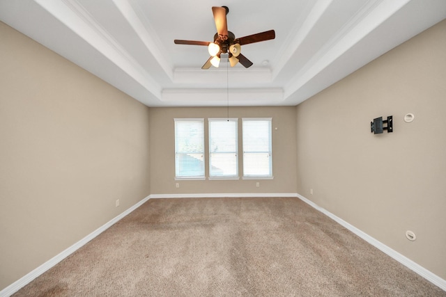 unfurnished room featuring ceiling fan, a raised ceiling, light colored carpet, and ornamental molding