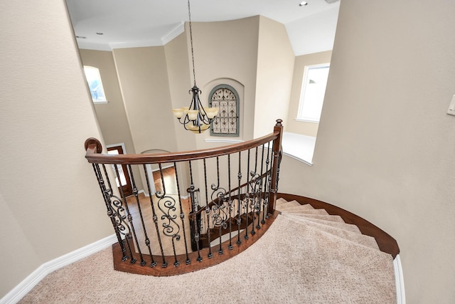 staircase featuring carpet flooring, crown molding, and a notable chandelier