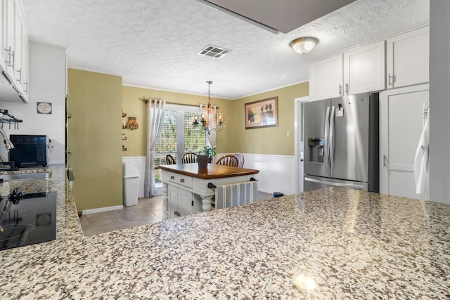 kitchen with white cabinetry, stainless steel fridge with ice dispenser, sink, and light stone counters