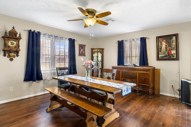 dining room featuring a textured ceiling, ceiling fan, dark wood-type flooring, and a wealth of natural light