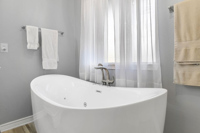 bathroom with hardwood / wood-style flooring and a tub to relax in