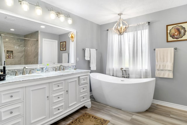 bathroom featuring a chandelier, vanity, hardwood / wood-style flooring, and plus walk in shower