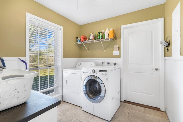 washroom featuring separate washer and dryer, light tile patterned floors, and a textured ceiling