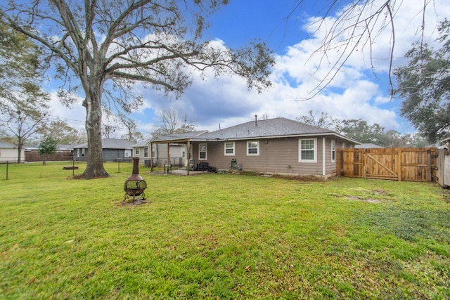 rear view of property featuring a fire pit and a yard