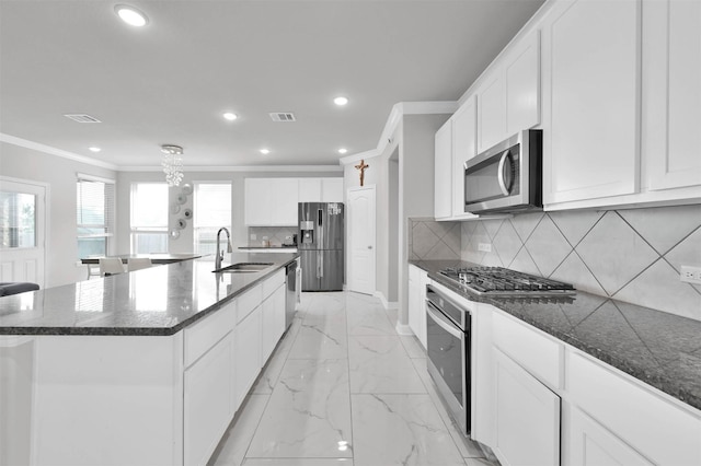 kitchen with appliances with stainless steel finishes, a large island with sink, decorative backsplash, and sink