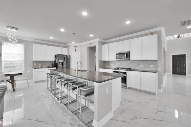 kitchen featuring sink, white cabinets, a kitchen bar, a kitchen island with sink, and appliances with stainless steel finishes