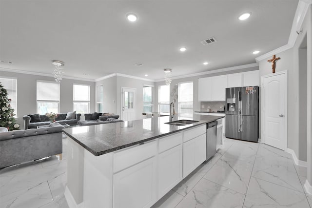 kitchen featuring sink, white cabinets, tasteful backsplash, a center island with sink, and appliances with stainless steel finishes