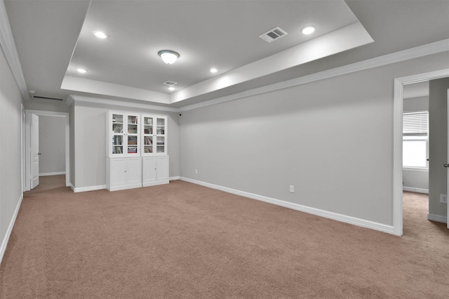 carpeted empty room featuring a raised ceiling and crown molding