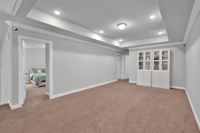 interior space with a tray ceiling, crown molding, and light colored carpet