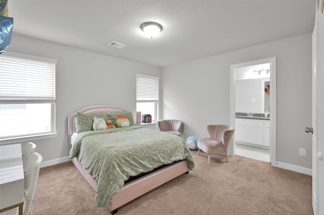 carpeted bedroom featuring sink and ensuite bath