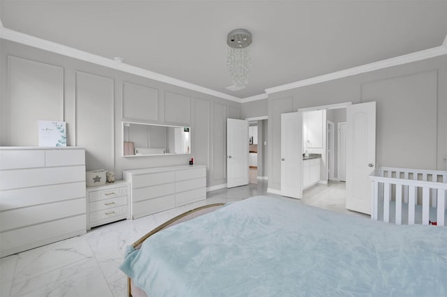 bedroom featuring ensuite bathroom, an inviting chandelier, and ornamental molding