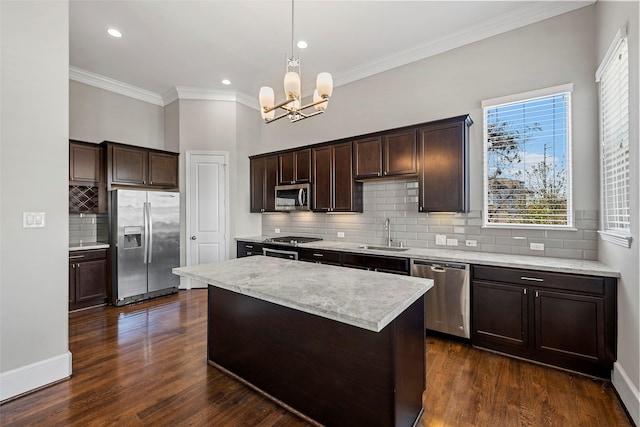 kitchen with appliances with stainless steel finishes, dark hardwood / wood-style flooring, sink, a kitchen island, and hanging light fixtures