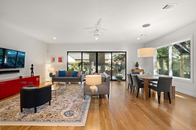 living room with light wood-type flooring, ceiling fan, and crown molding