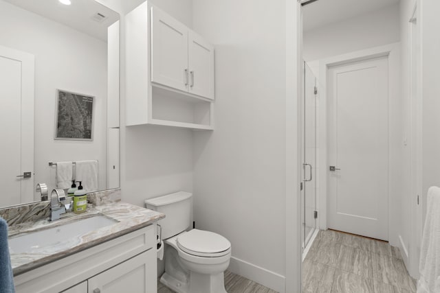 bathroom with toilet, a shower with shower door, and vanity