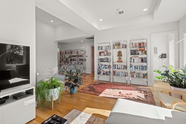 living room featuring light wood-type flooring and a raised ceiling