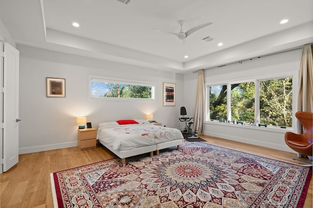 bedroom featuring ceiling fan, a tray ceiling, and multiple windows