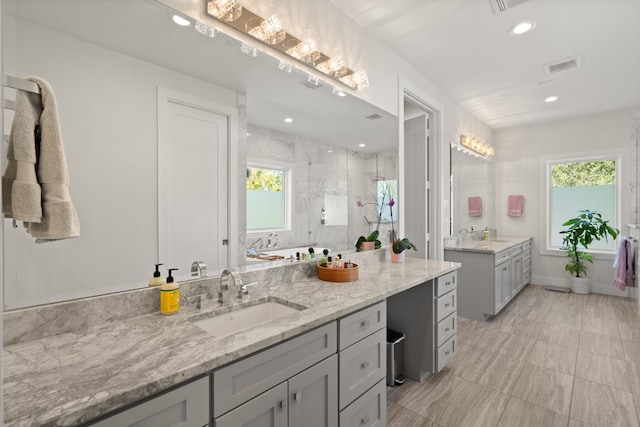 bathroom with a tile shower and vanity