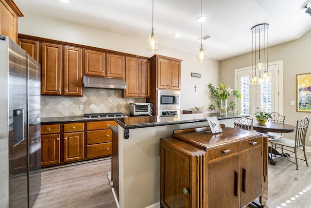 kitchen featuring stainless steel appliances, decorative light fixtures, a center island, and backsplash