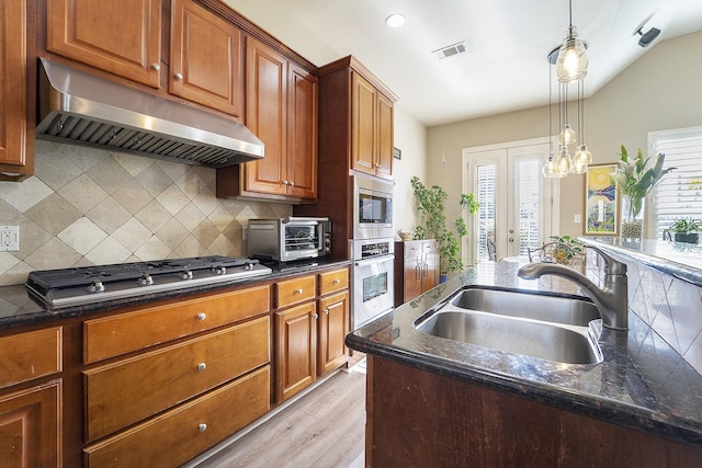 kitchen featuring appliances with stainless steel finishes, french doors, range hood, sink, and backsplash