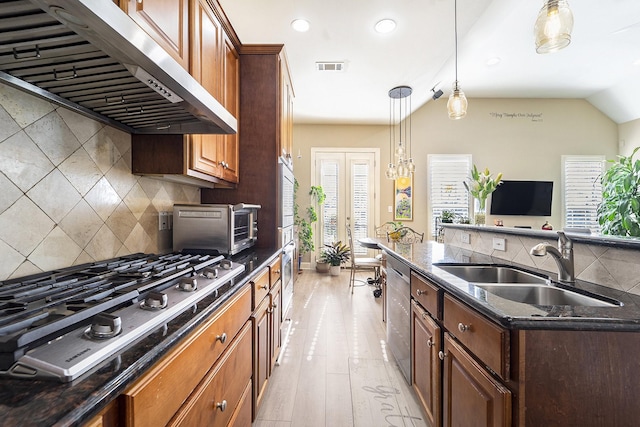 kitchen featuring sink, french doors, exhaust hood, pendant lighting, and appliances with stainless steel finishes