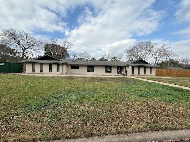 view of front of home with brick siding, fence, and a front yard