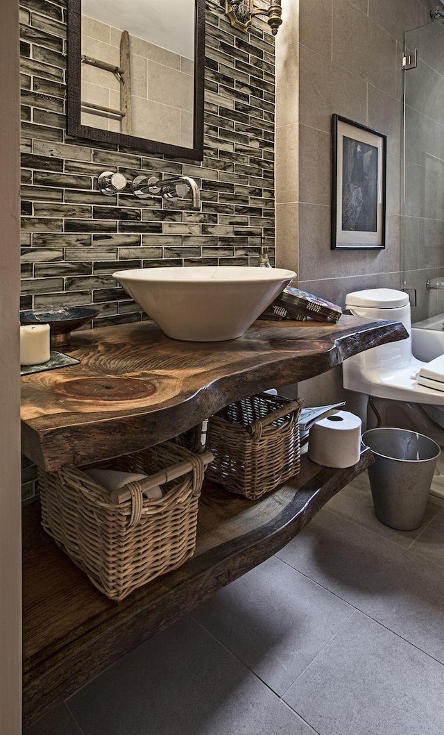 full bath with toilet, a sink, tile walls, and decorative backsplash