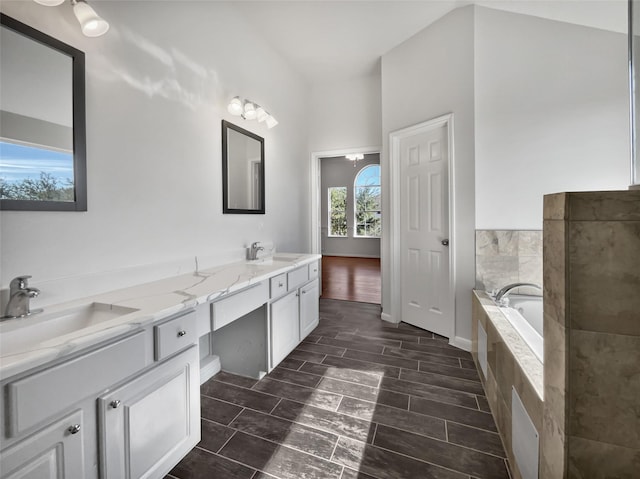 bathroom featuring tiled tub and vanity