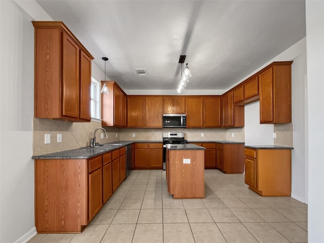 kitchen featuring appliances with stainless steel finishes, light tile patterned floors, a kitchen island, sink, and decorative light fixtures