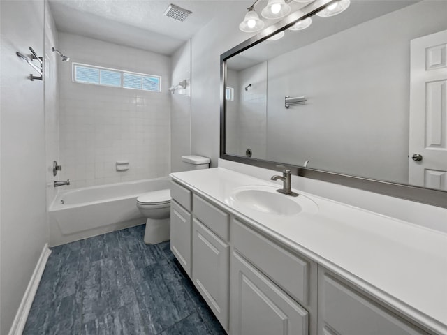 full bathroom featuring vanity, hardwood / wood-style floors, tiled shower / bath combo, and toilet