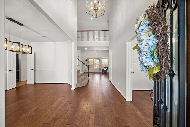 foyer entrance with a chandelier, a high ceiling, and dark wood-type flooring