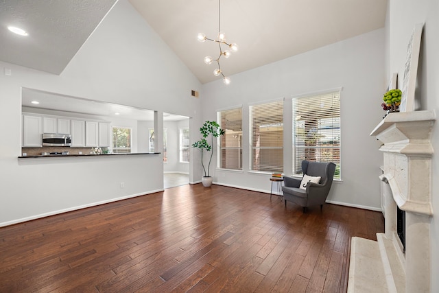 unfurnished room featuring a fireplace, high vaulted ceiling, dark hardwood / wood-style floors, and a notable chandelier