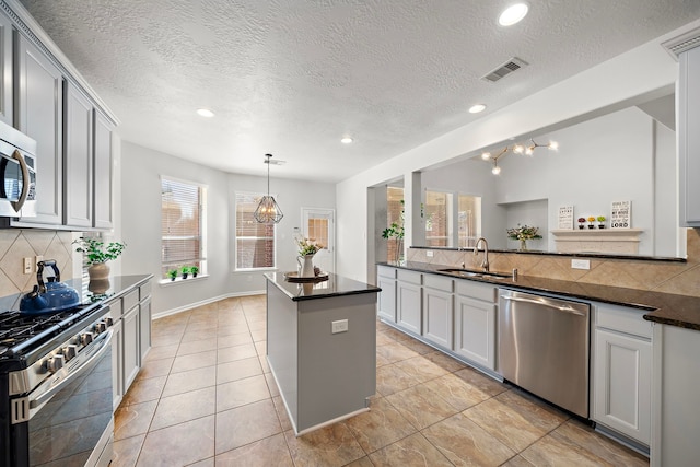 kitchen with a textured ceiling, backsplash, sink, and stainless steel appliances