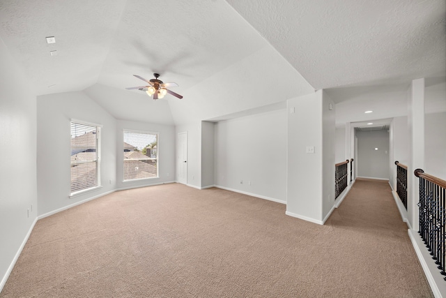 carpeted spare room with ceiling fan, a textured ceiling, and vaulted ceiling