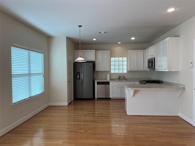 kitchen featuring white cabinets, sink, hanging light fixtures, appliances with stainless steel finishes, and kitchen peninsula