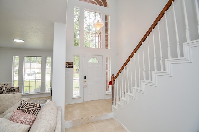 tiled foyer featuring crown molding and an inviting chandelier