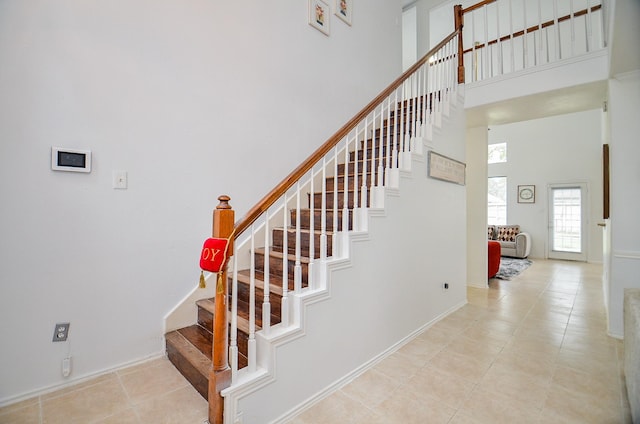 staircase featuring tile patterned floors and a high ceiling